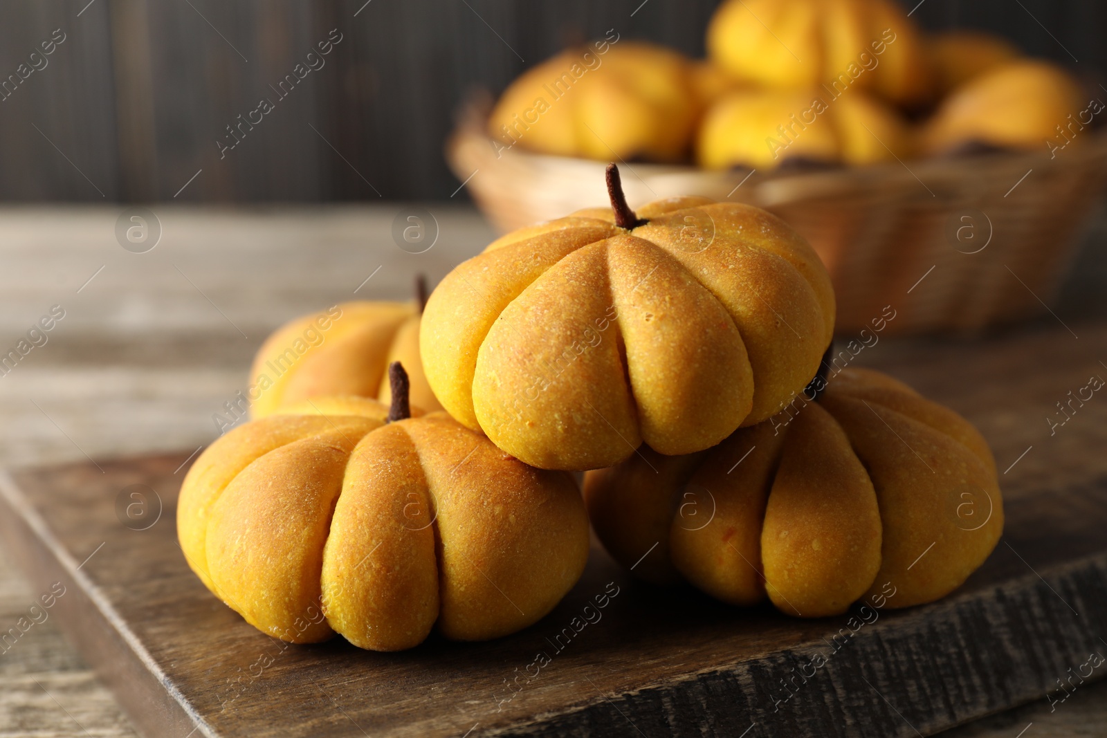 Photo of Tasty pumpkin shaped buns on wooden table, closeup