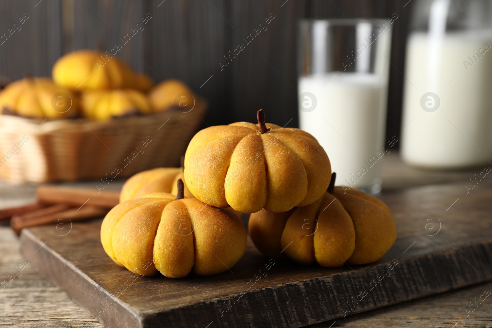 Photo of Tasty pumpkin shaped buns on wooden table, closeup