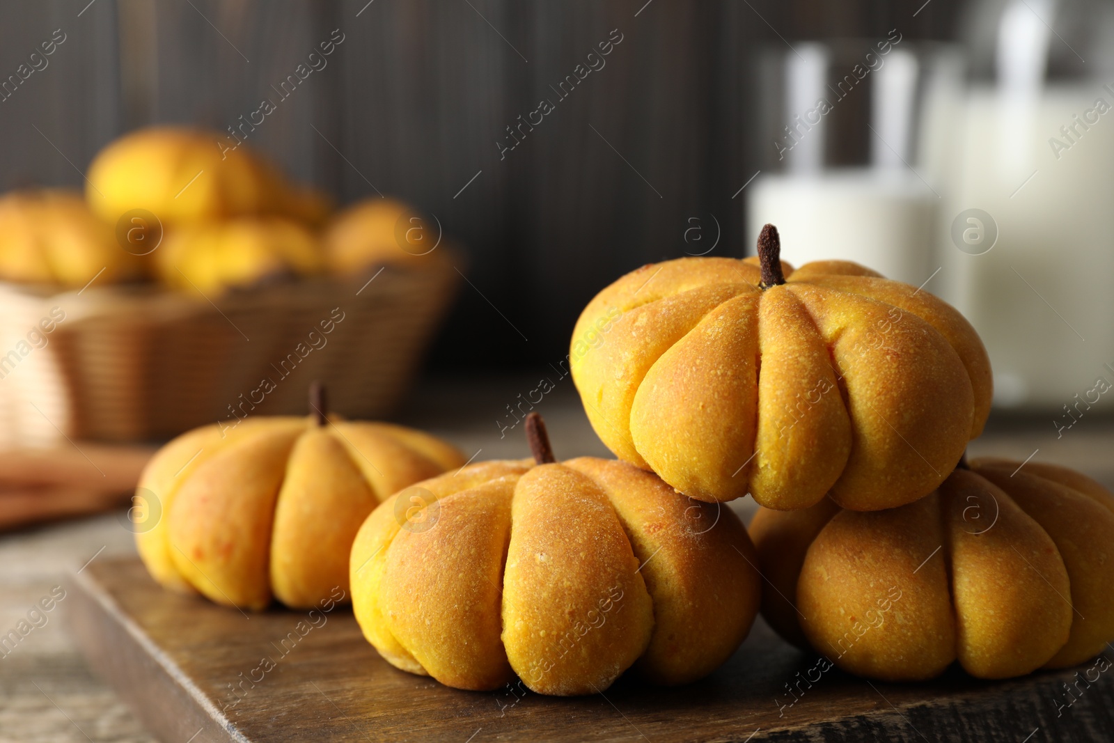 Photo of Tasty pumpkin shaped buns on wooden table, closeup