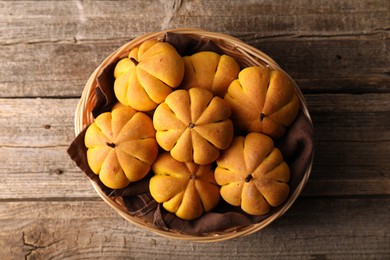 Wicker basket with tasty pumpkin shaped buns on wooden table, top view