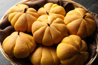 Photo of Tasty pumpkin shaped buns in wicker basket, closeup