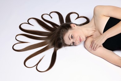 Photo of Beautiful young woman with hair in shape of hearts on white background