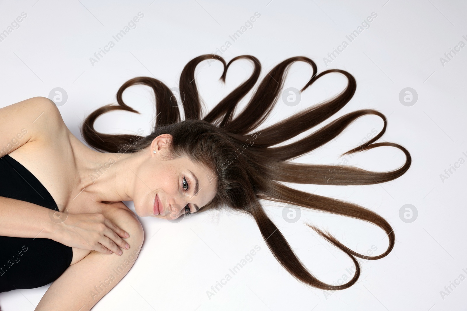 Photo of Beautiful young woman with hair in shape of hearts on white background