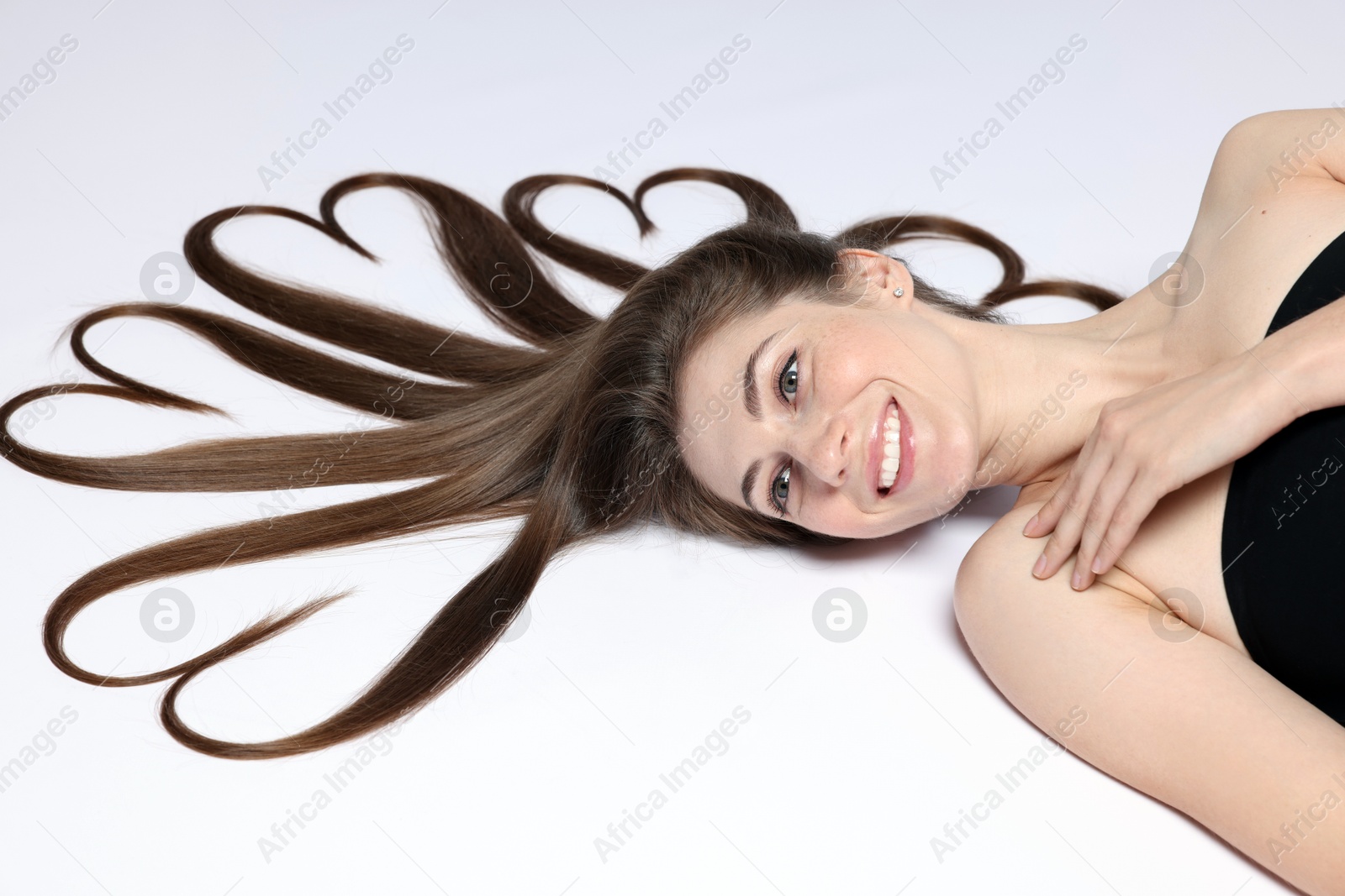 Photo of Beautiful young woman with hair in shape of hearts on white background