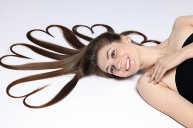 Photo of Beautiful young woman with hair in shape of hearts on white background