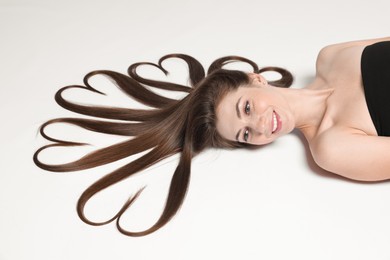 Photo of Beautiful young woman with hair in shape of hearts on white background