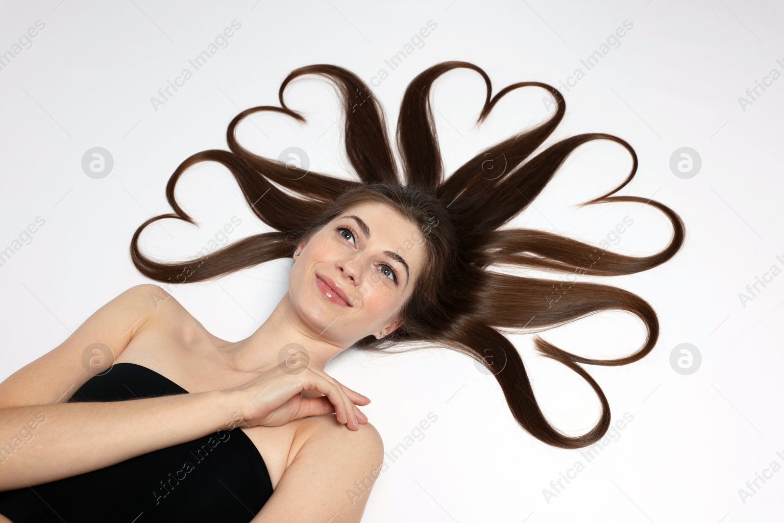 Photo of Beautiful young woman with hair in shape of hearts on white background