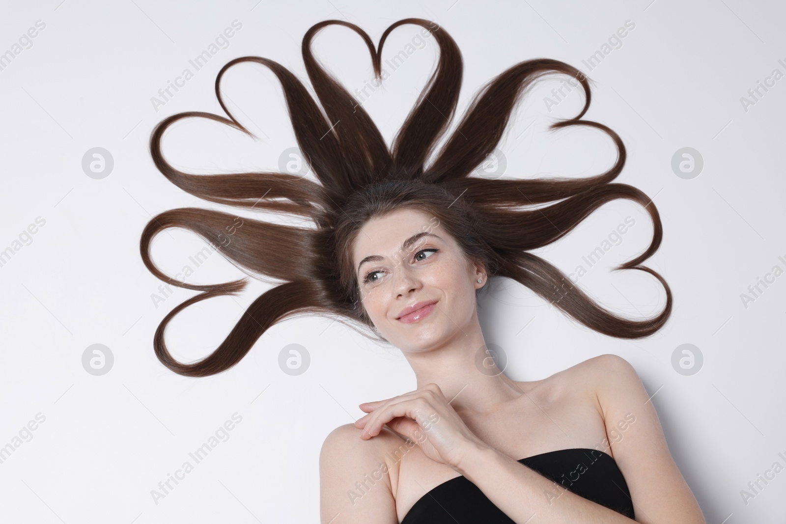 Photo of Beautiful young woman with hair in shape of hearts on white background