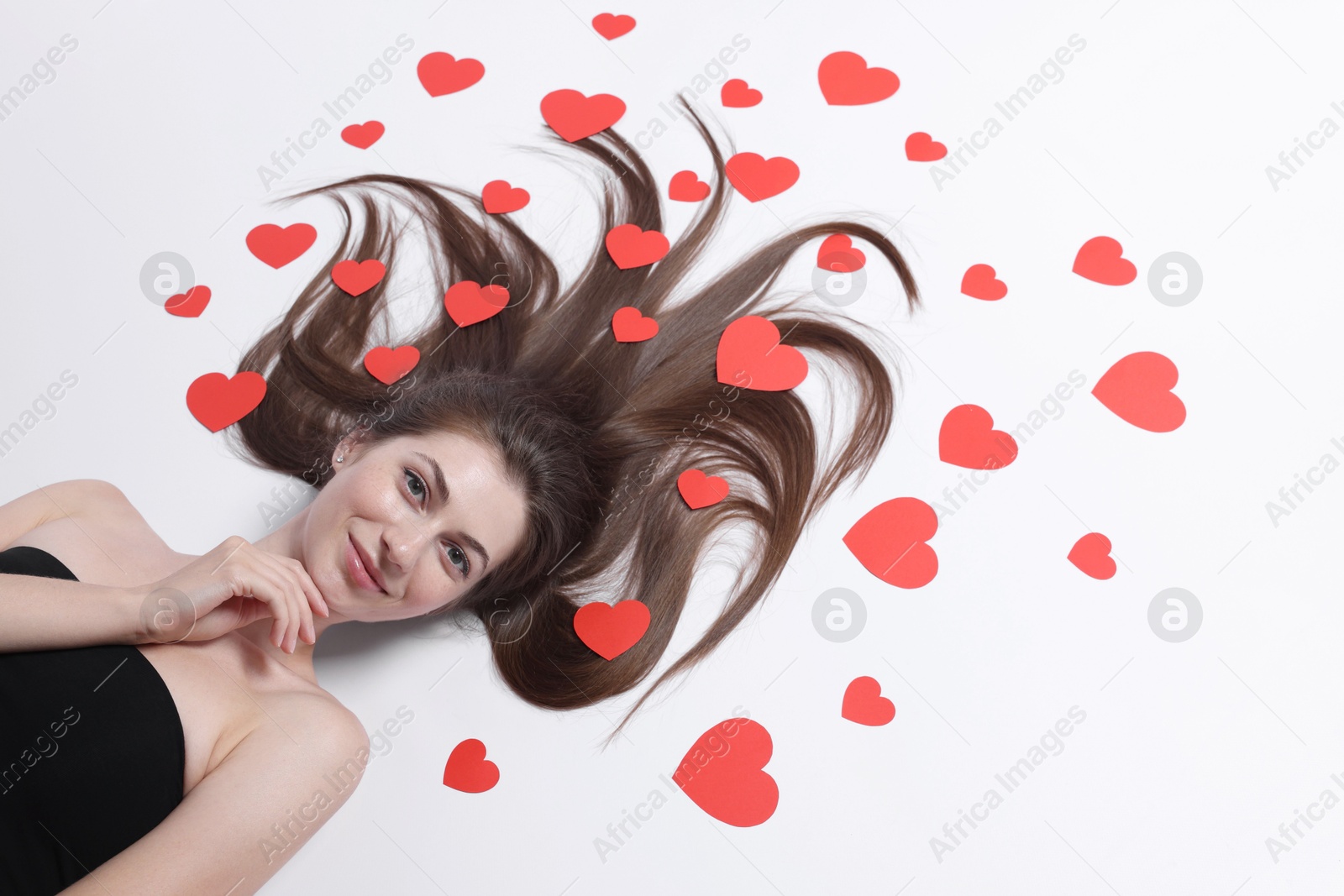 Photo of Beautiful young woman with long hair and red paper hearts on white background