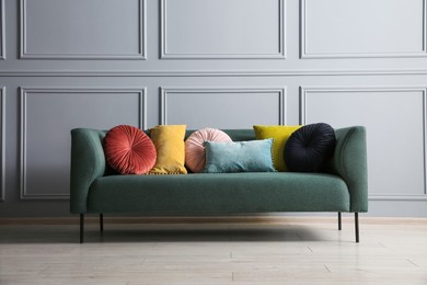 Stylish sofa with cushions near grey wall