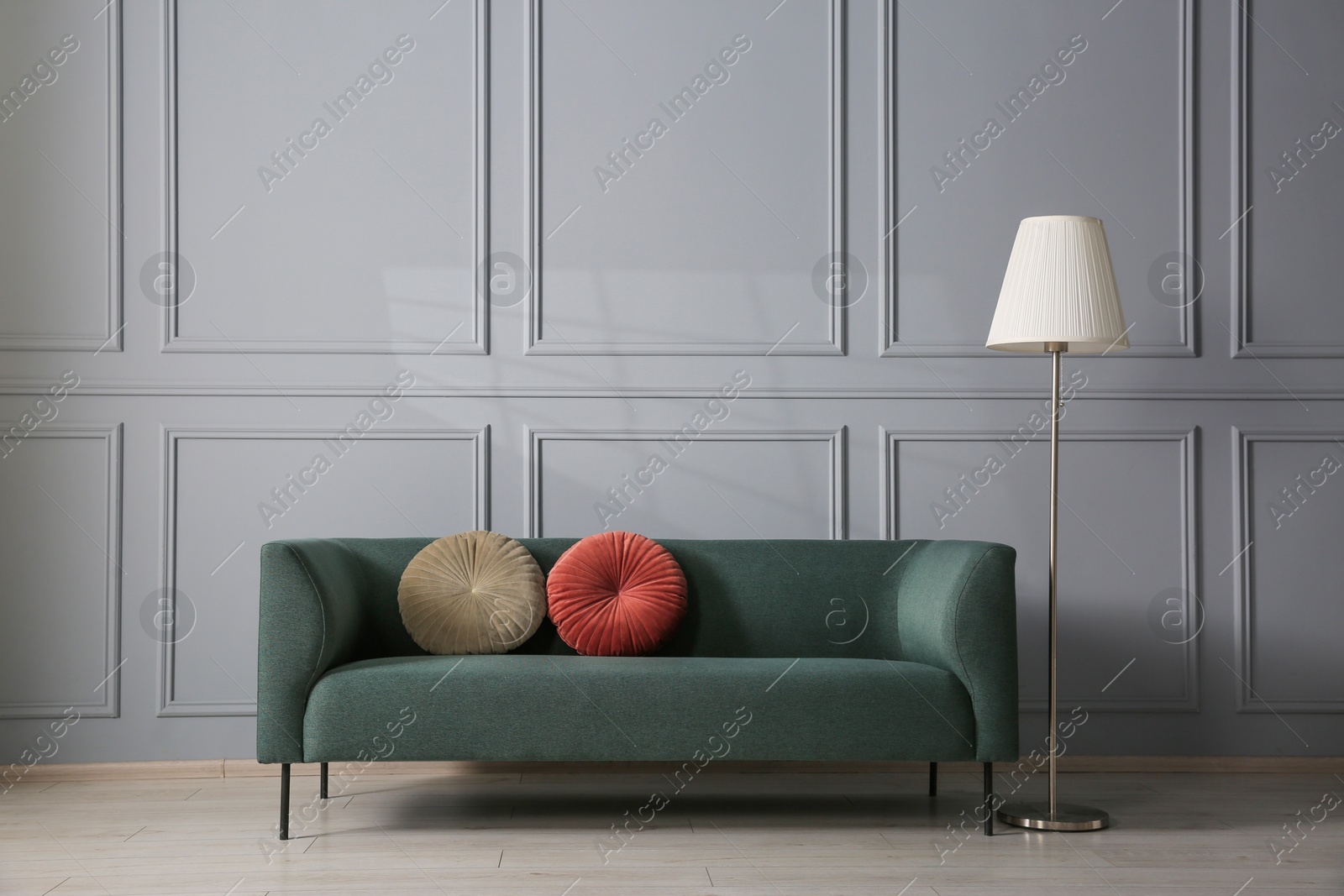 Photo of Comfortable sofa and lamp near grey wall in room