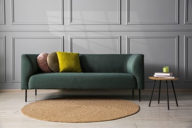 Photo of Comfortable sofa and side table near grey wall in room