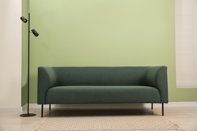 Photo of Stylish sofa and lamp near green wall indoors