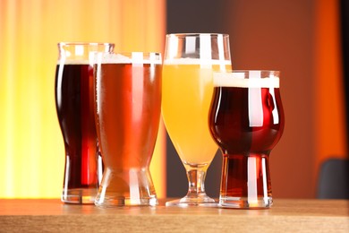 Photo of Glasses with different types of beer on wooden table indoors