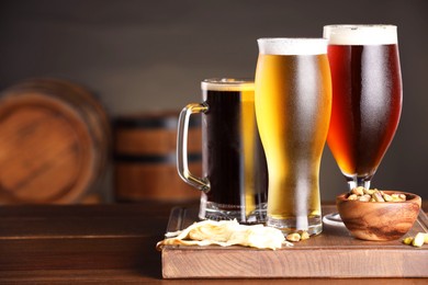 Photo of Glasses with different types of beer and snacks on wooden table in bar. Space for text