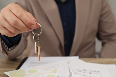 Photo of Real estate agent with house key at table, closeup