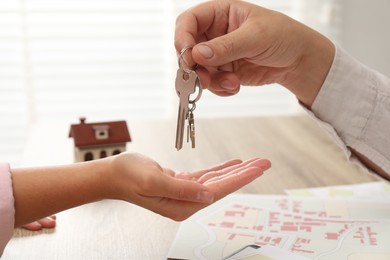 Real estate agent giving house key to new owner at table, closeup