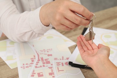 Real estate agent giving house key to new owner at table, closeup