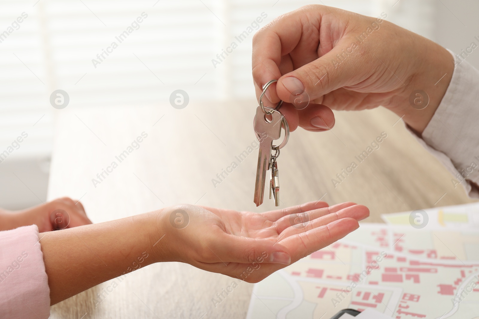 Photo of Real estate agent giving house key to new owner at table, closeup