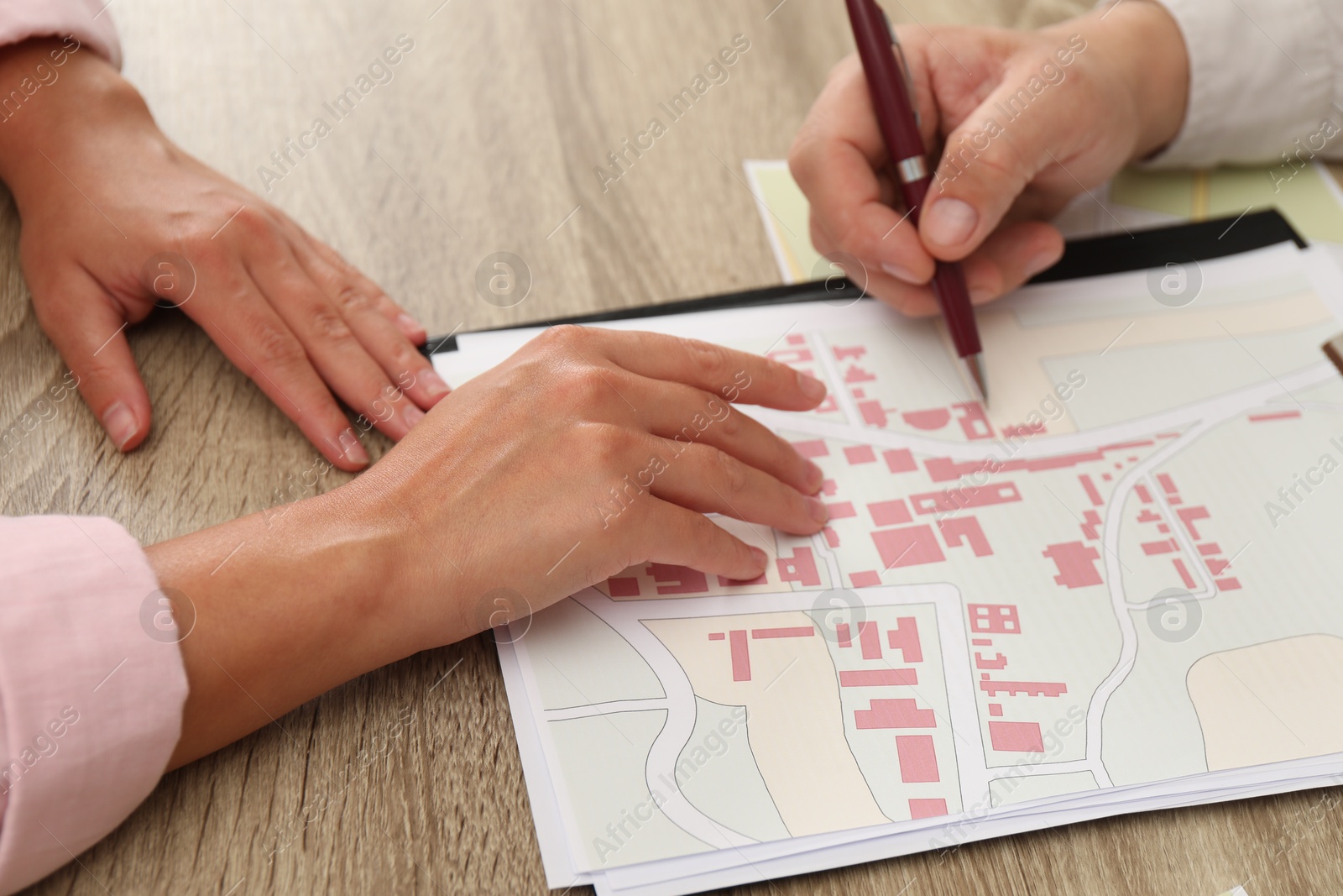 Photo of Real estate agent working with client at wooden table, closeup