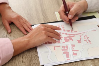 Photo of Real estate agent working with client at wooden table, closeup