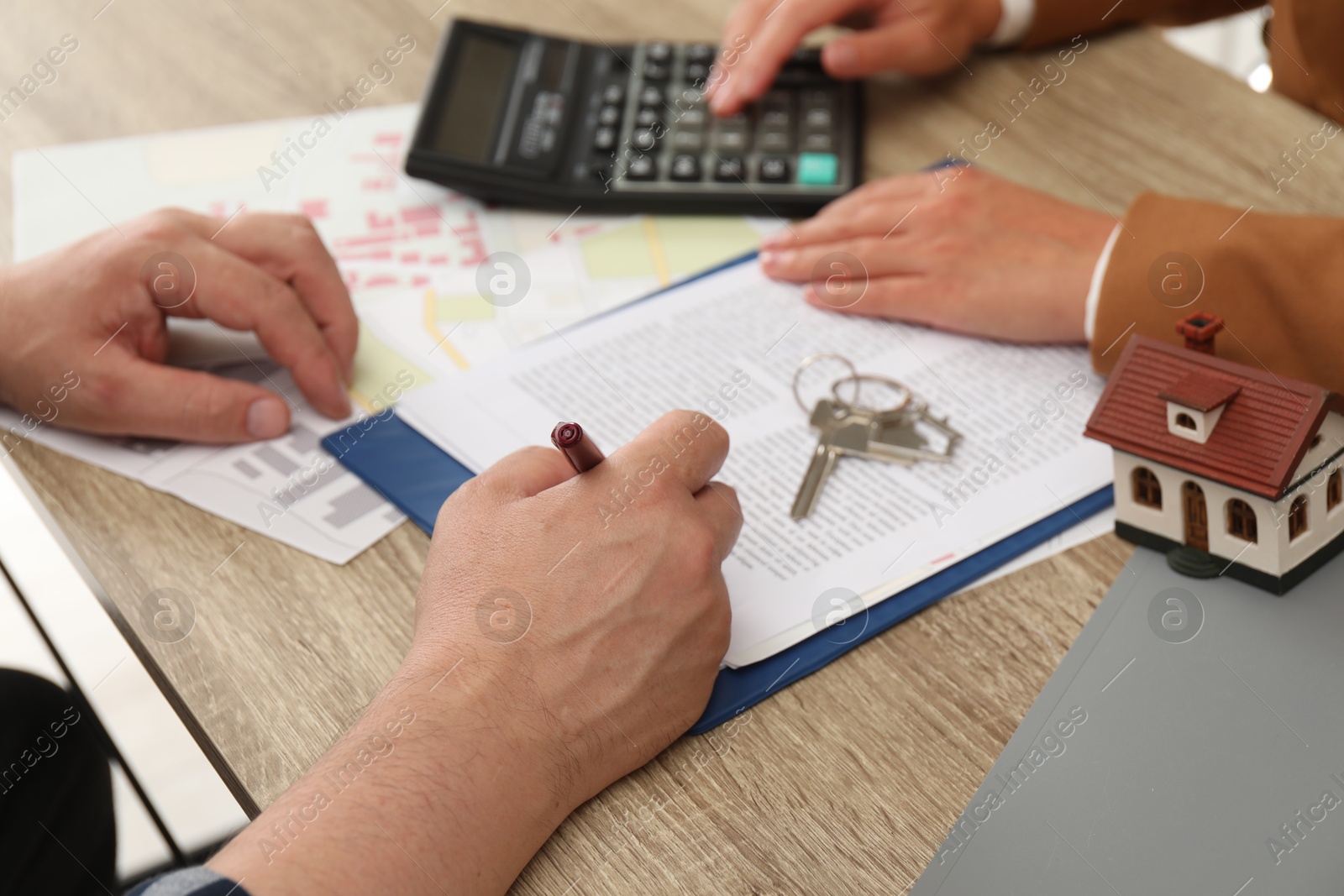 Photo of Real estate agent working with client at wooden table, closeup