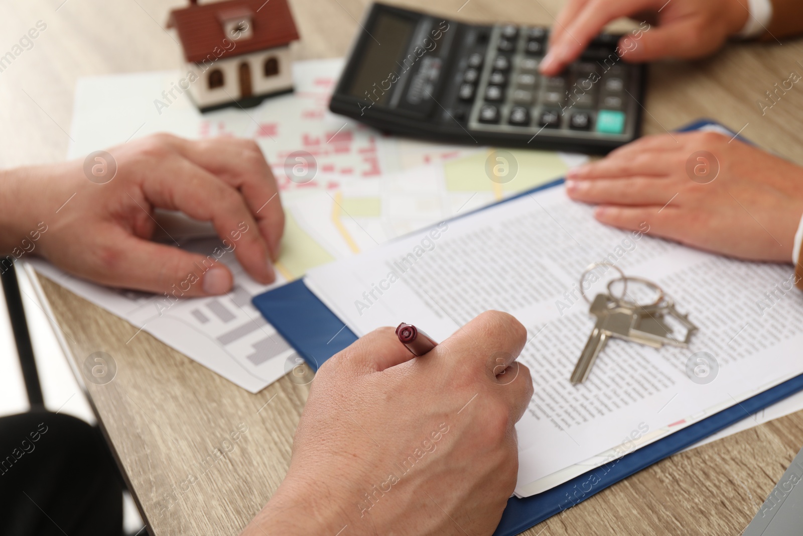 Photo of Real estate agent working with client at wooden table, closeup