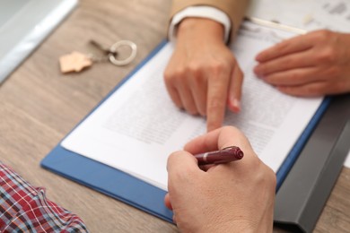 Photo of Real estate agent working with client at wooden table, closeup