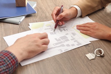 Real estate agent working with client at wooden table, closeup