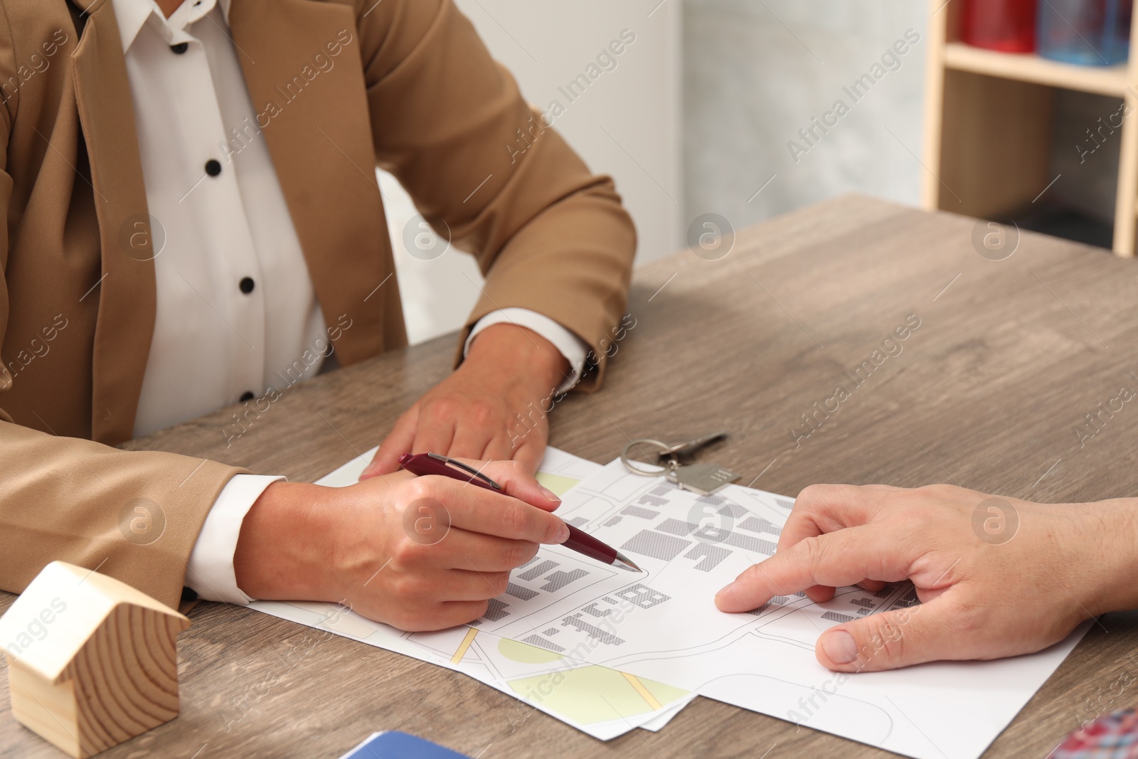 Photo of Real estate agent working with client at wooden table, closeup