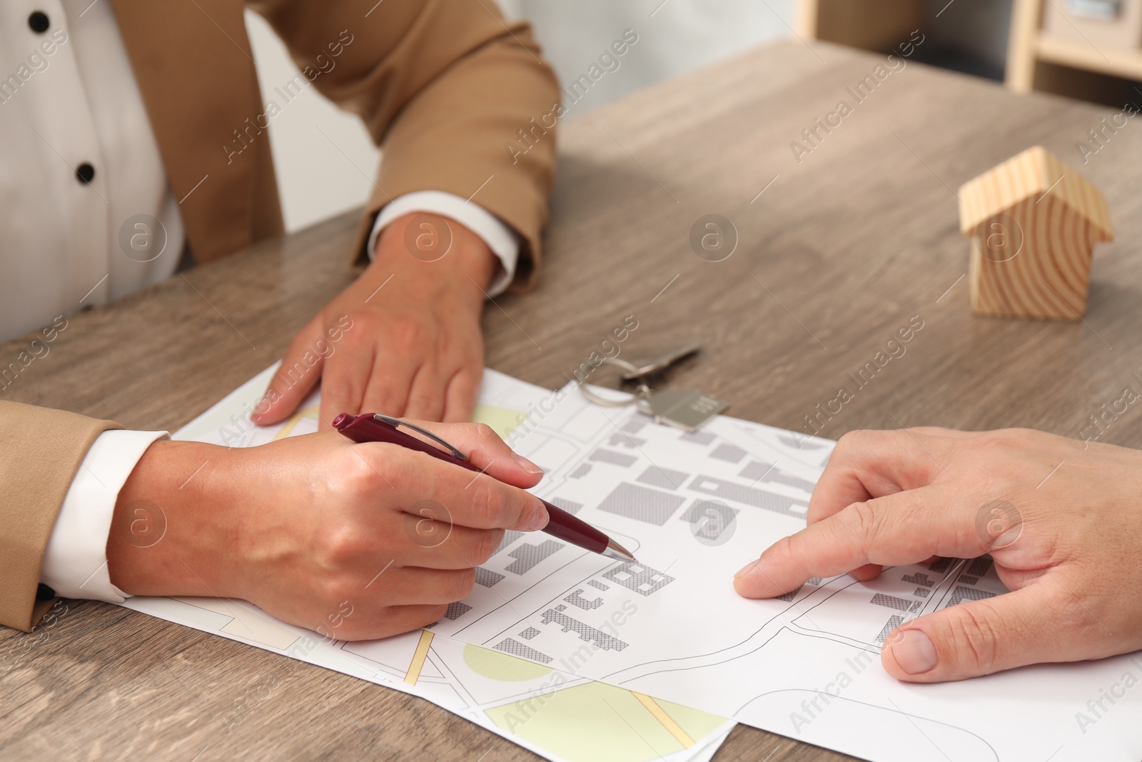 Photo of Real estate agent working with client at wooden table, closeup