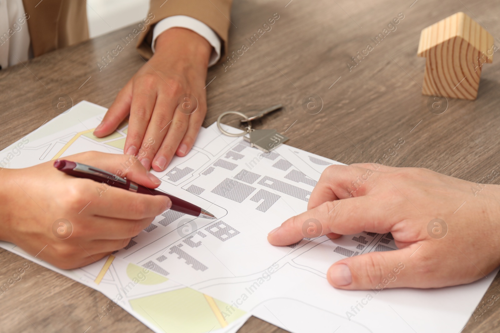 Photo of Real estate agent working with client at wooden table, closeup