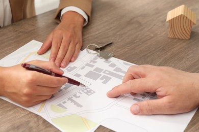 Photo of Real estate agent working with client at wooden table, closeup