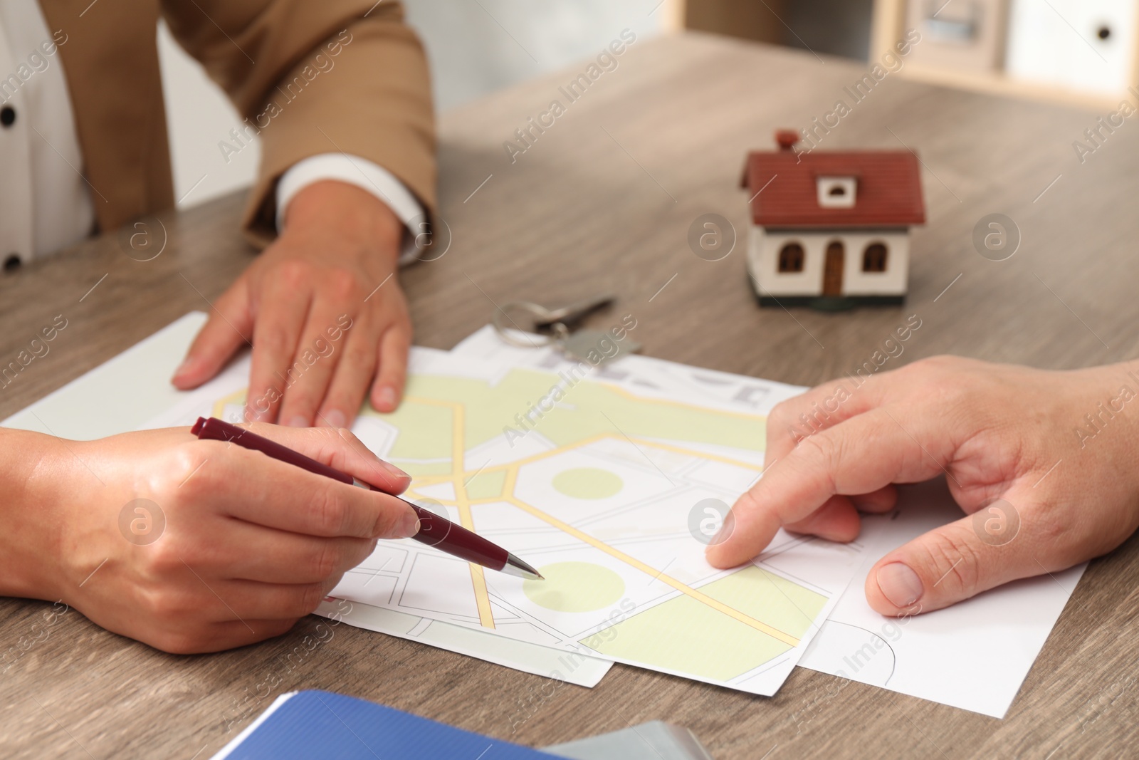 Photo of Real estate agent working with client at wooden table, closeup