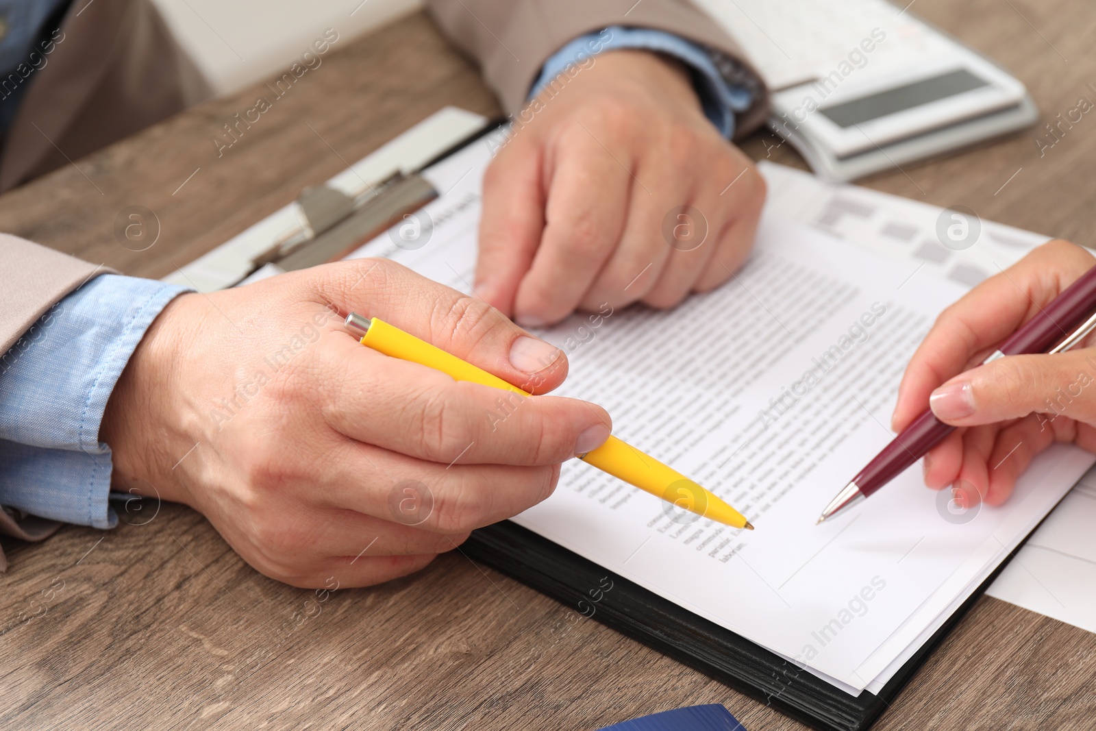 Photo of Real estate agent working with client at wooden table, closeup