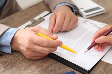 Real estate agent working with client at wooden table, closeup