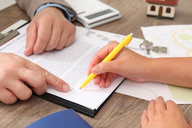 Photo of Real estate agent working with client at wooden table, closeup