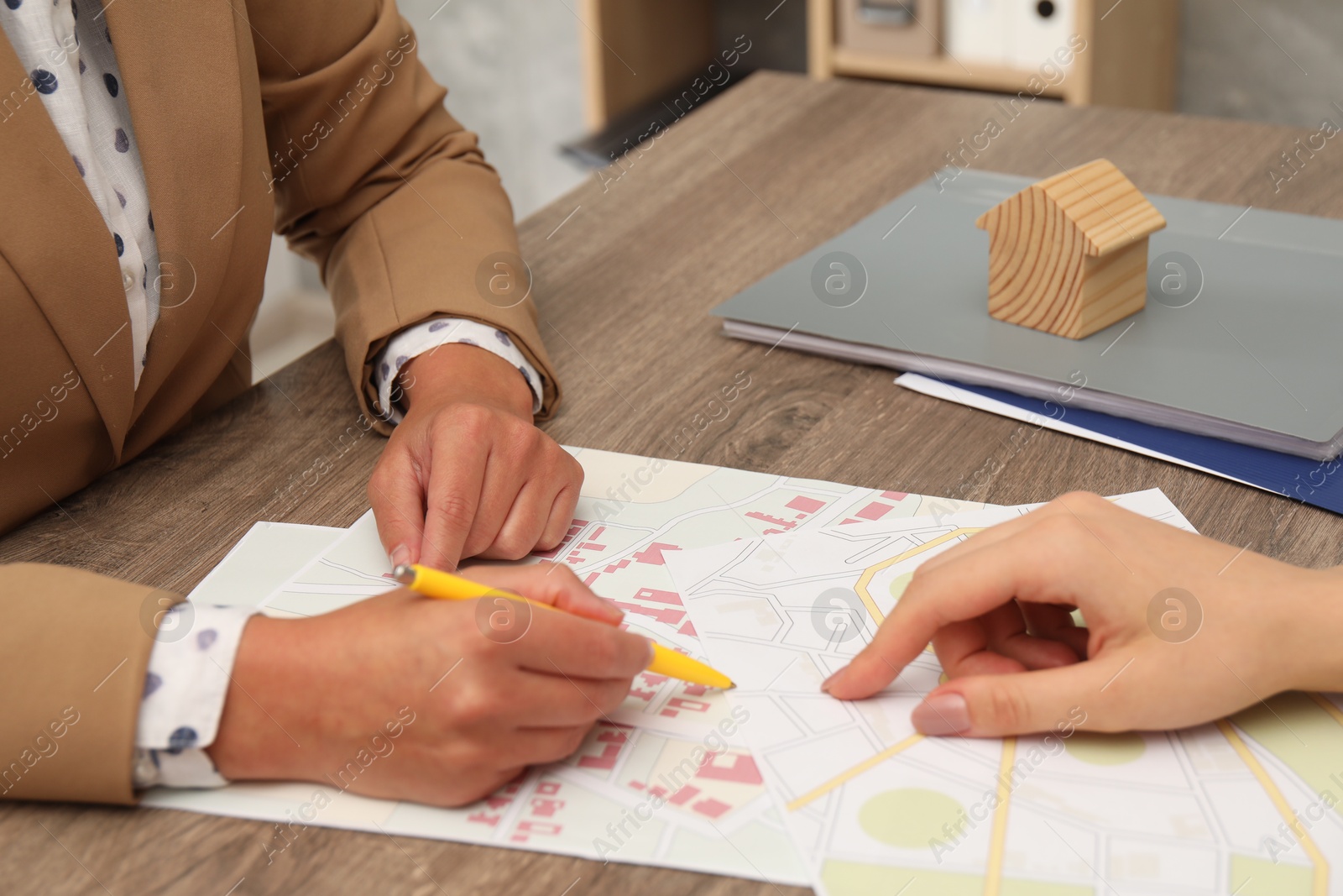 Photo of Real estate agent working with client at wooden table, closeup