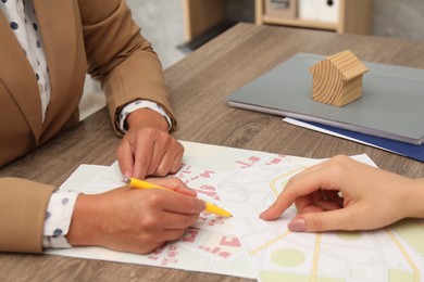 Real estate agent working with client at wooden table, closeup