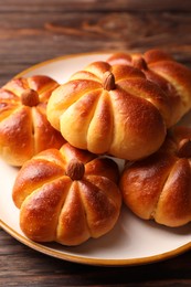 Photo of Tasty pumpkin shaped buns on wooden table, closeup