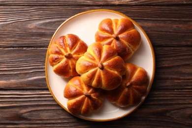 Photo of Tasty pumpkin shaped buns on wooden table, top view