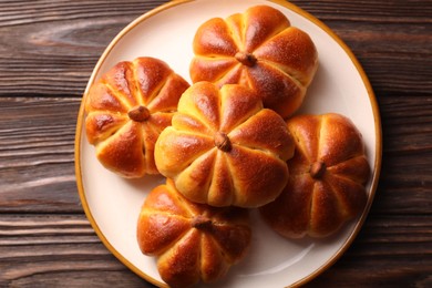 Photo of Tasty pumpkin shaped buns on wooden table, top view