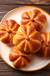 Photo of Tasty pumpkin shaped buns on wooden table, top view