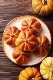 Photo of Tasty pumpkin shaped buns and ingredients on wooden table, flat lay