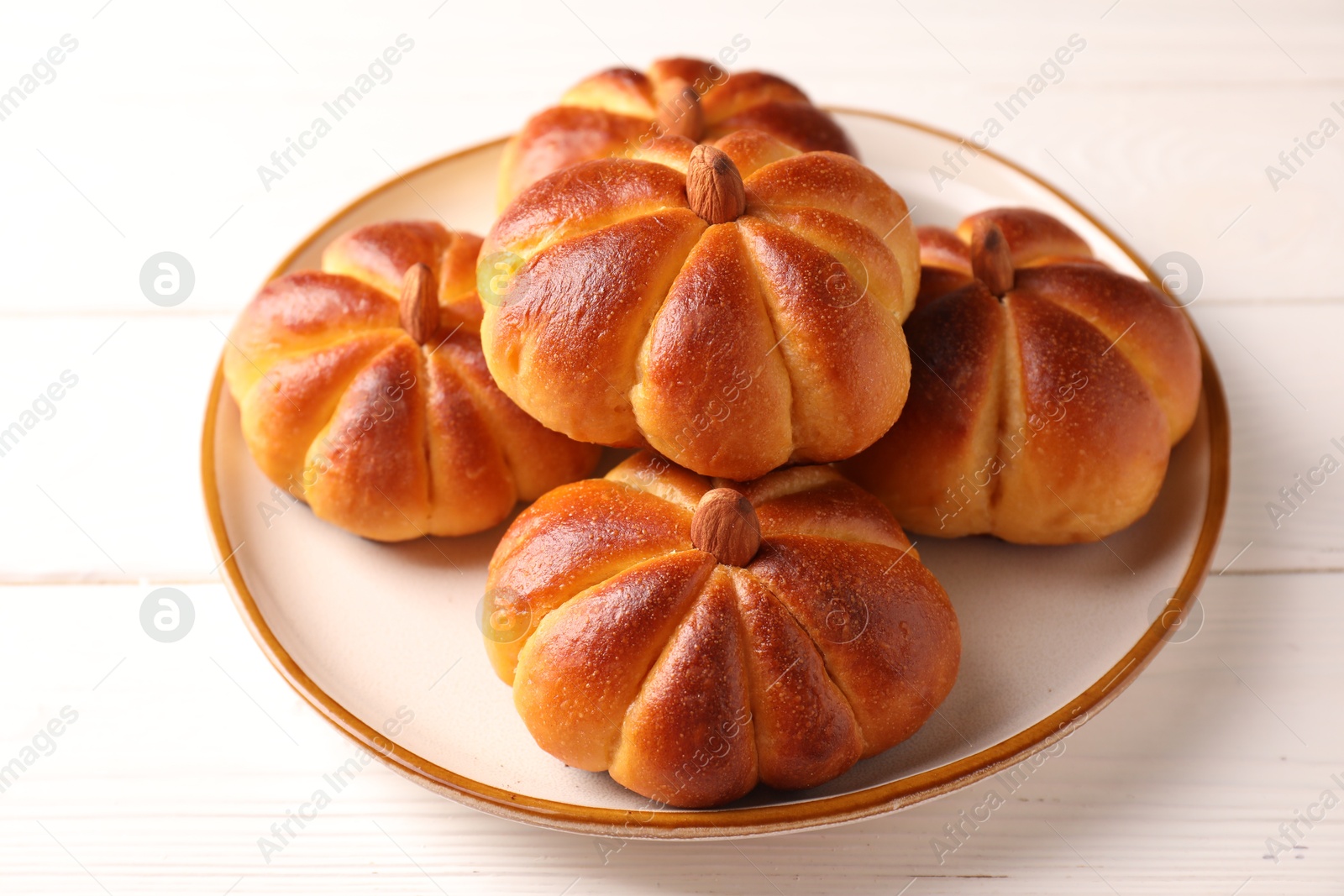 Photo of Tasty pumpkin shaped buns on white wooden table, closeup