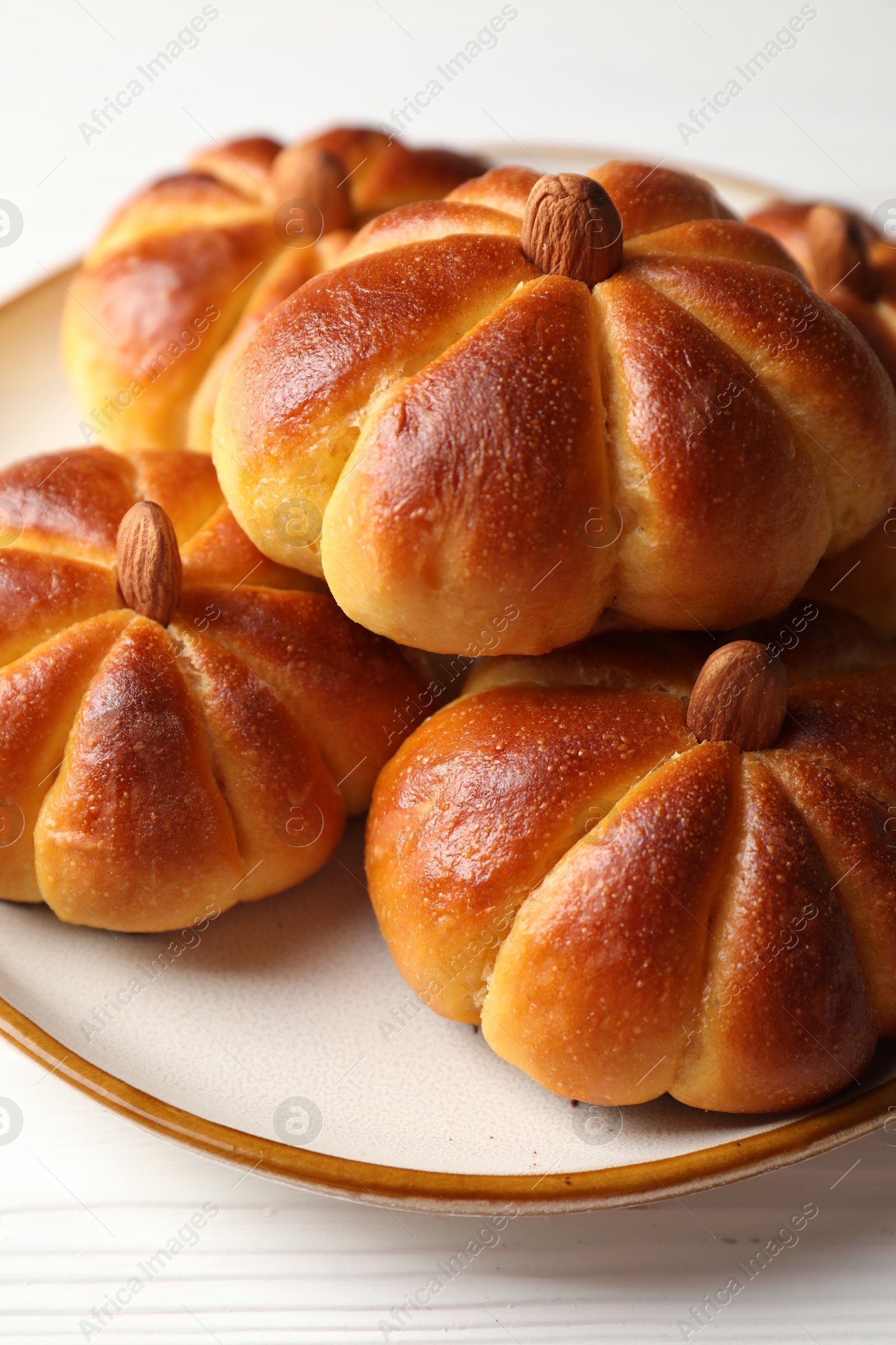 Photo of Tasty pumpkin shaped buns on white wooden table, closeup