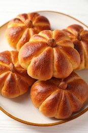 Photo of Tasty pumpkin shaped buns on white wooden table, closeup