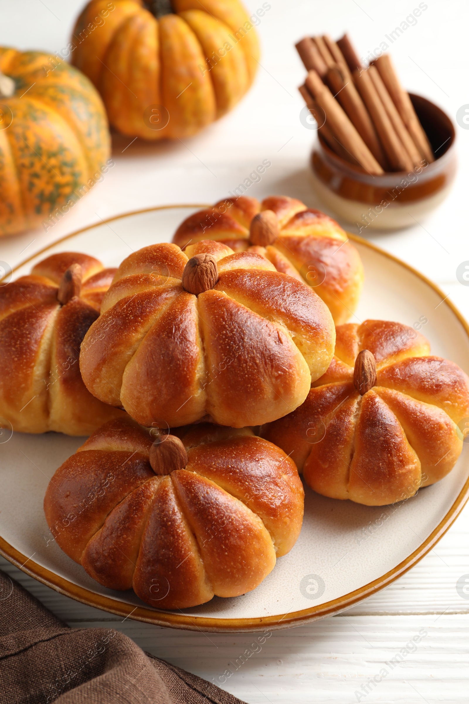 Photo of Tasty pumpkin shaped buns and ingredients on white wooden table, closeup