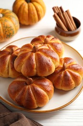 Photo of Tasty pumpkin shaped buns and ingredients on white wooden table, closeup