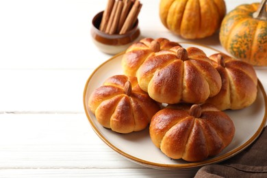 Photo of Tasty pumpkin shaped buns and ingredients on white wooden table, closeup